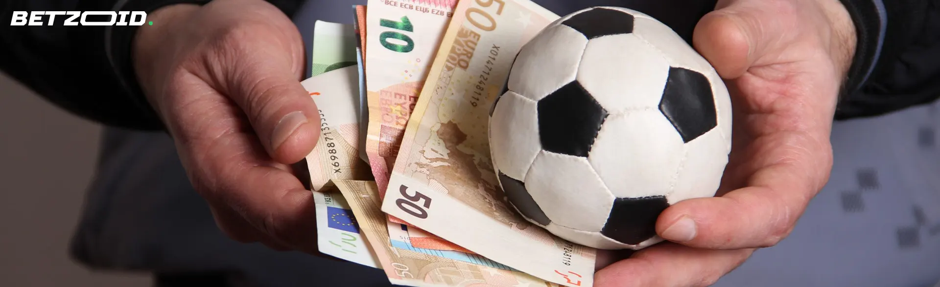 Manos sosteniendo billetes de euro y una pelota de fútbol en corredores de apuestas en España.