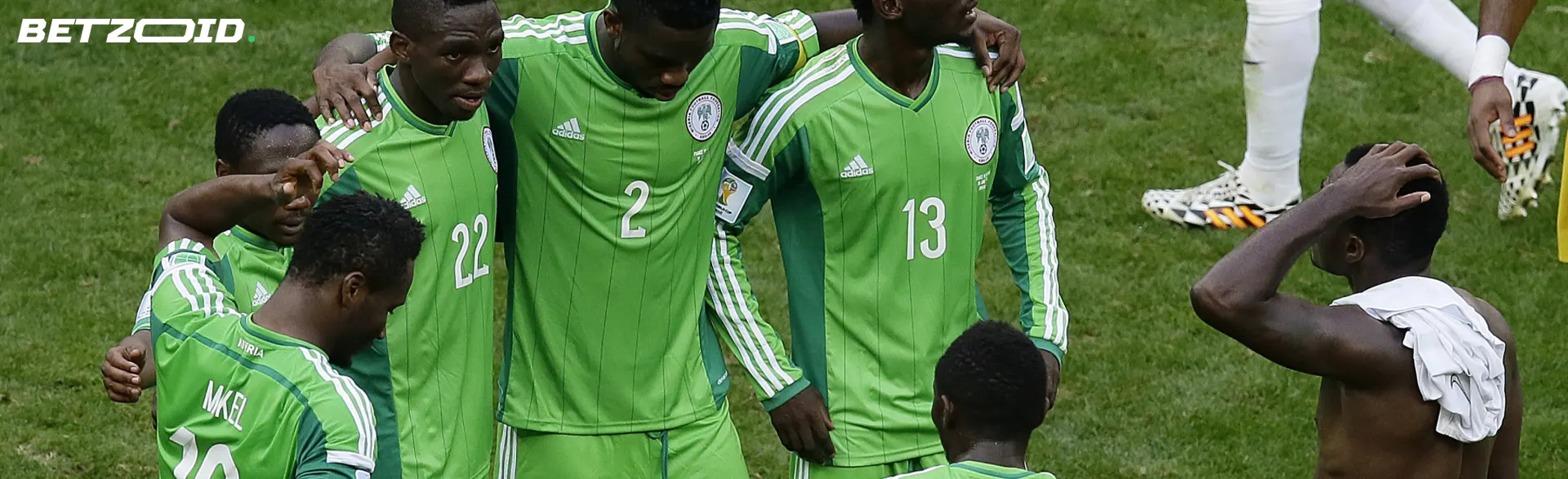 Football players in green uniforms discuss tactics before the match.
