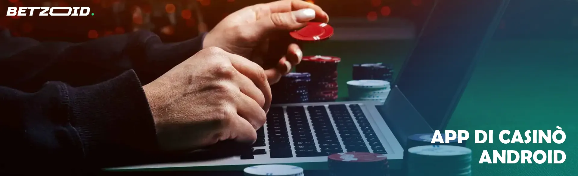 Mani che tengono fiches da poker davanti al computer portatile con molte fiches sul tavolo.