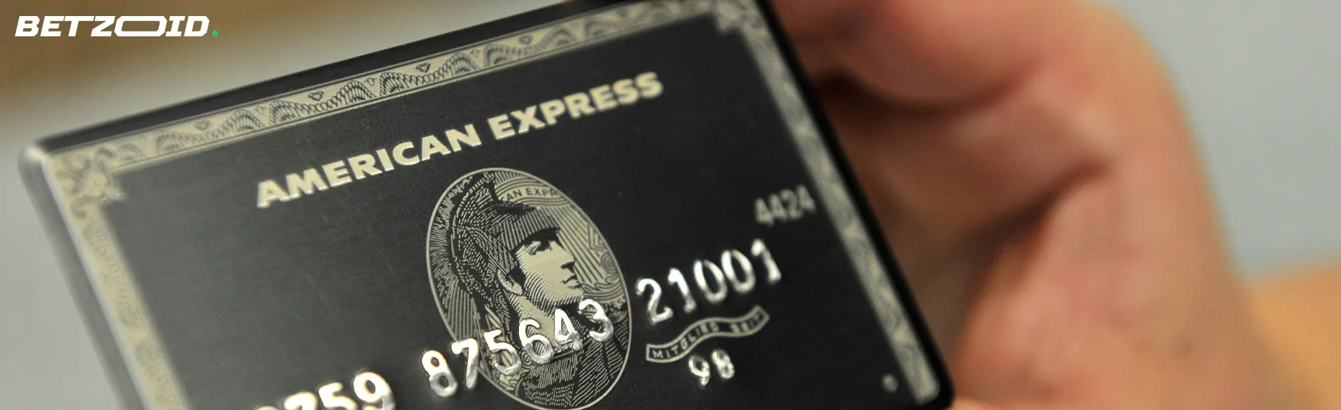 Un hombre sostiene una tarjeta American Express en su mano.