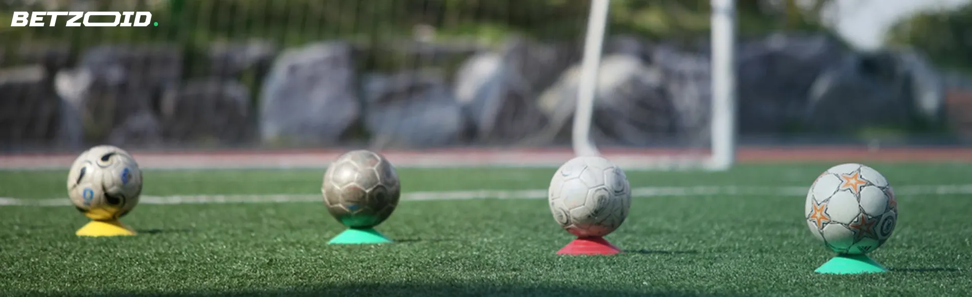 Cuatro balones en el campo de fútbol frente a la portería para pronósticos de fútbol para hoy.