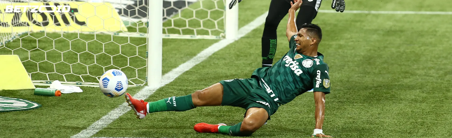 A football player tries to kick the ball near the goal.