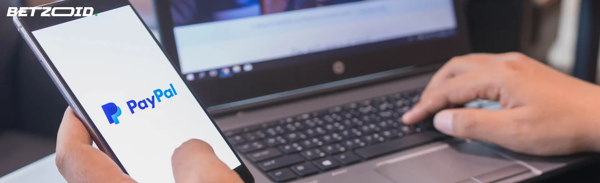 Smartphone with PayPal logo in human hand.