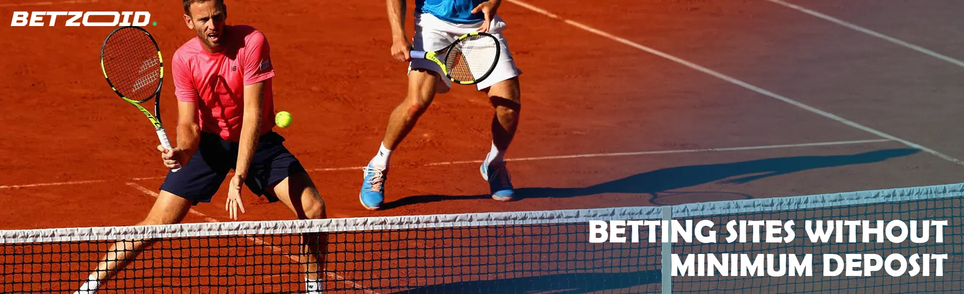 Doubles tennis game on a red clay court.