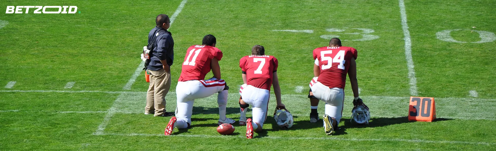 American football players are kneeling on the field.