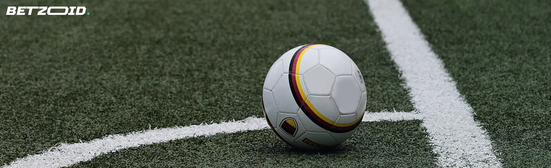 Soccer ball on a green artificial turf at the corner boundary line.