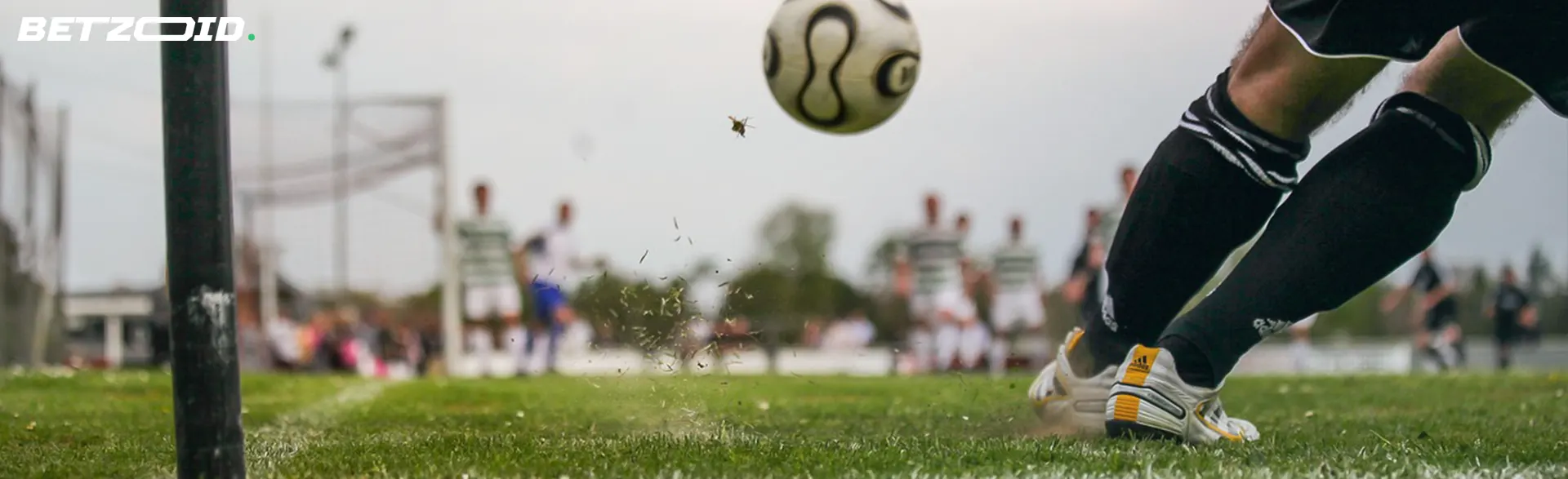 A dynamic moment in a football game captured, highlighting a player about to strike a football towards the net.