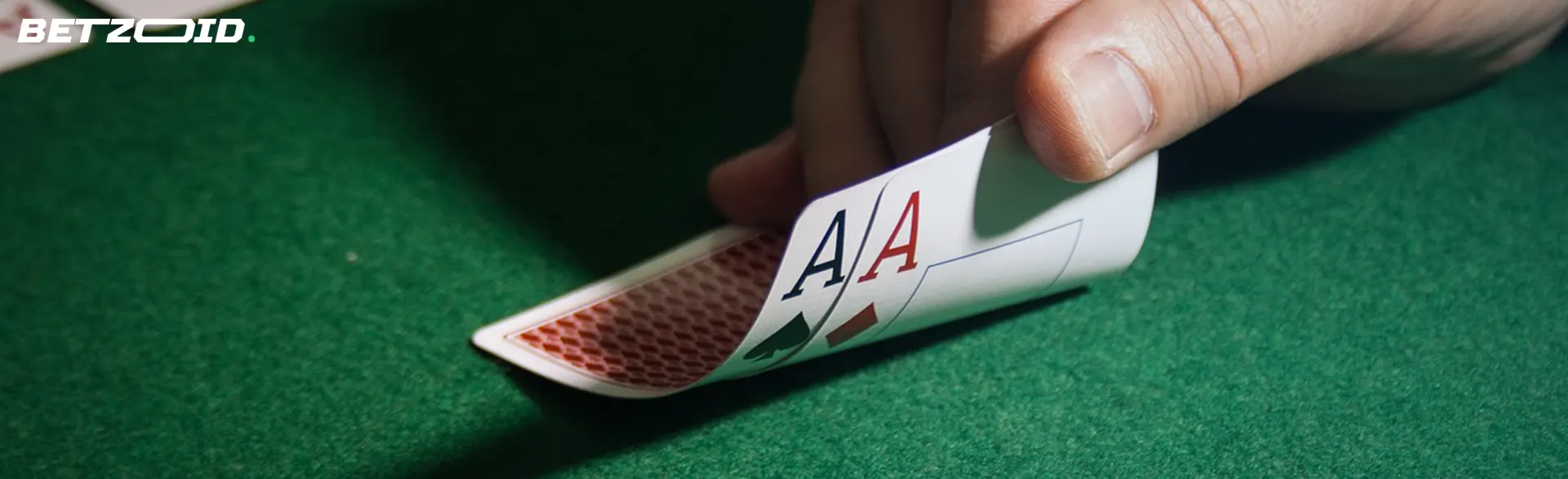 A hand revealing two aces during a poker game on a green felt table.