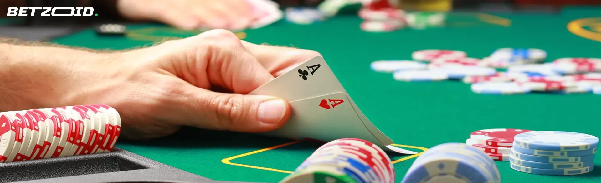 A player's hand holding two aces at a poker table, with chips in the background.