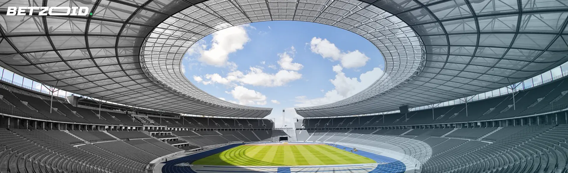 Panoramic view of a large, modern stadium with a partially covered roof and rows of empty seats.