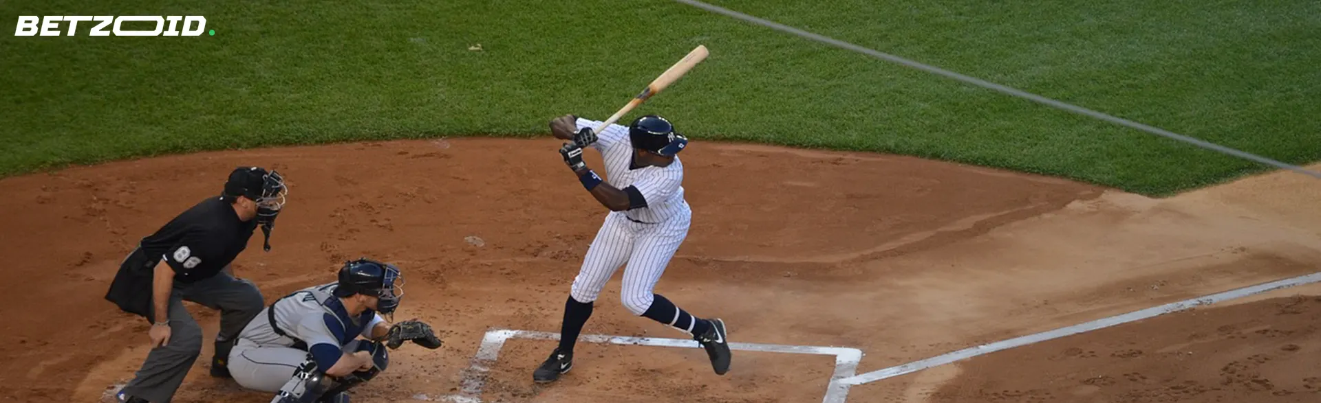 A baseball player preparing to swing at the plate, with a catcher and umpire in position behind him.