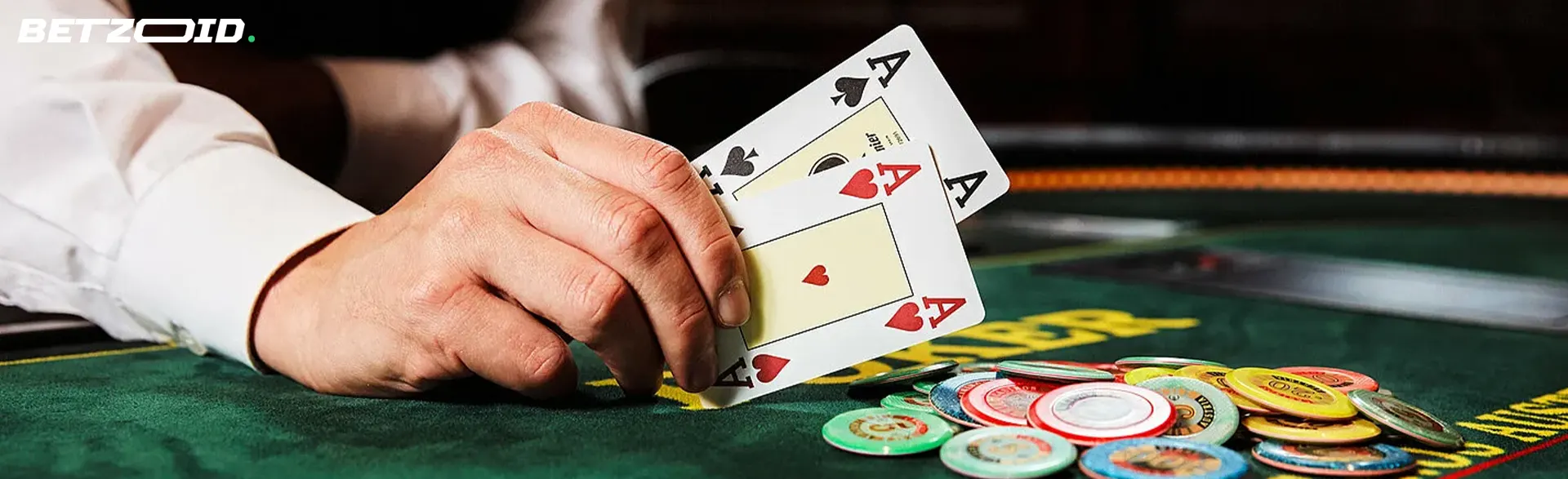 Hráč drží karty nad žetony kasina.
