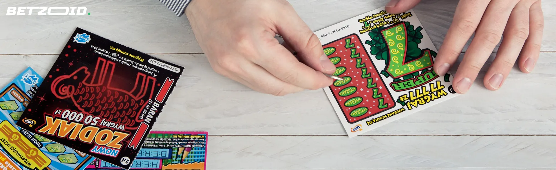 Osoba wyciera zdrapki loteryjne.