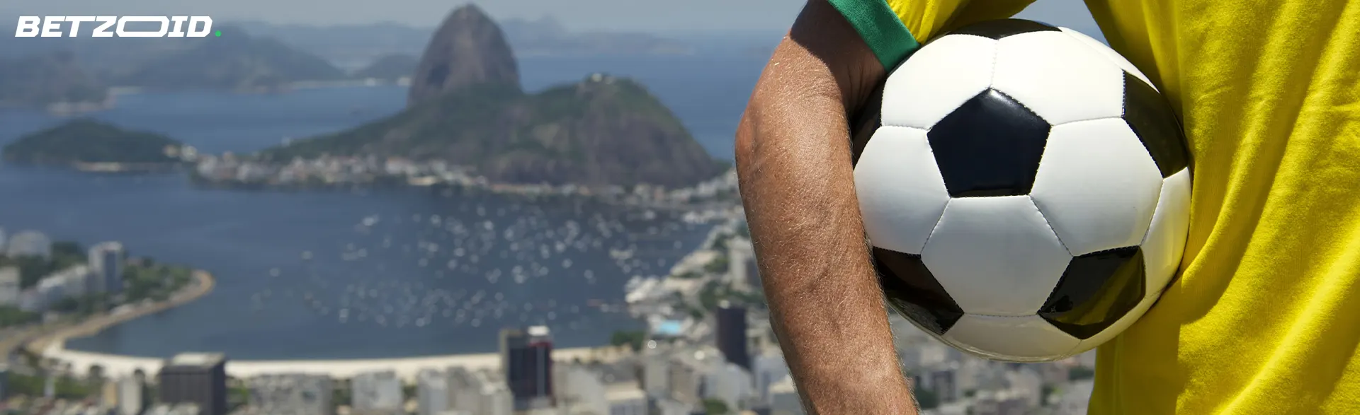 Um homem segura uma bola de futebol tendo como pano de fundo a cidade do Rio de Janeiro.