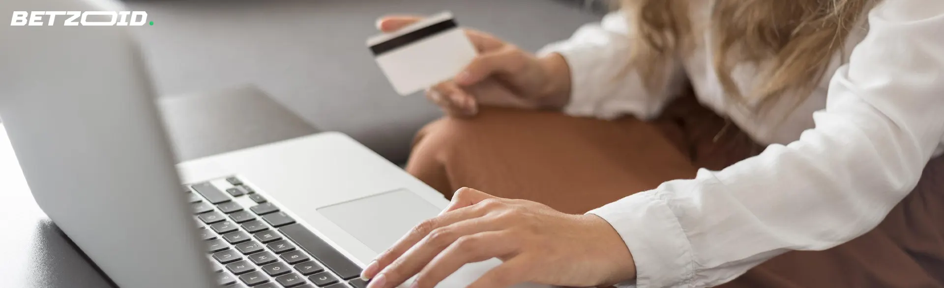 Um homem está segurando um cartão bancário na frente de um laptop.