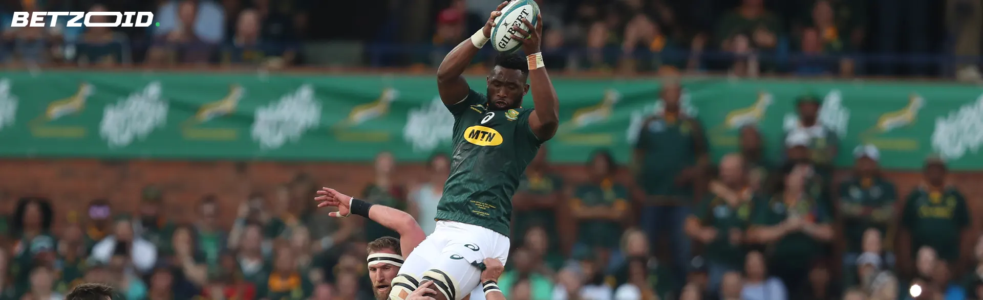 A rugby player catches the ball during a game on the field.