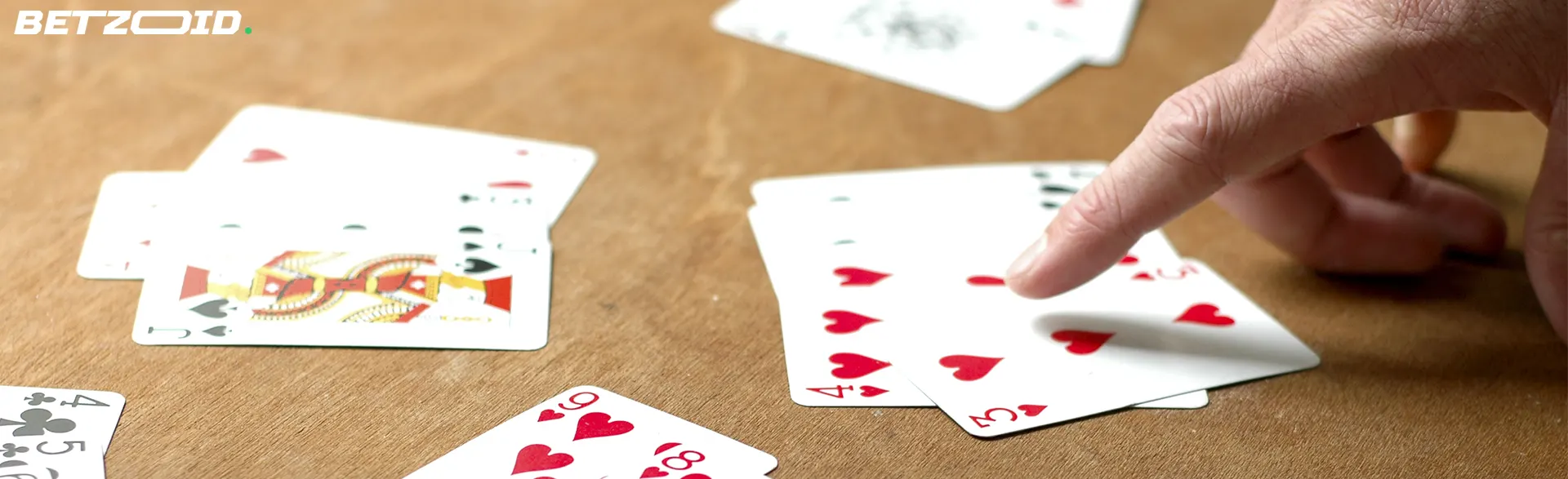 A hand pointing at playing cards on a table, illustrating the gaming options available at casinos in Nunavut, Canada.