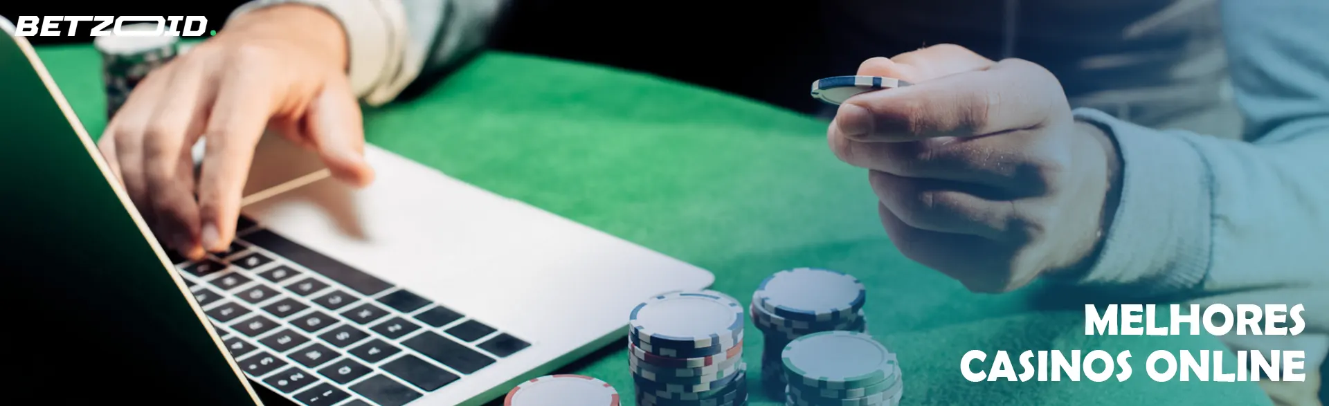 Um jogador segura fichas de casino ao lado de um computador portátil.