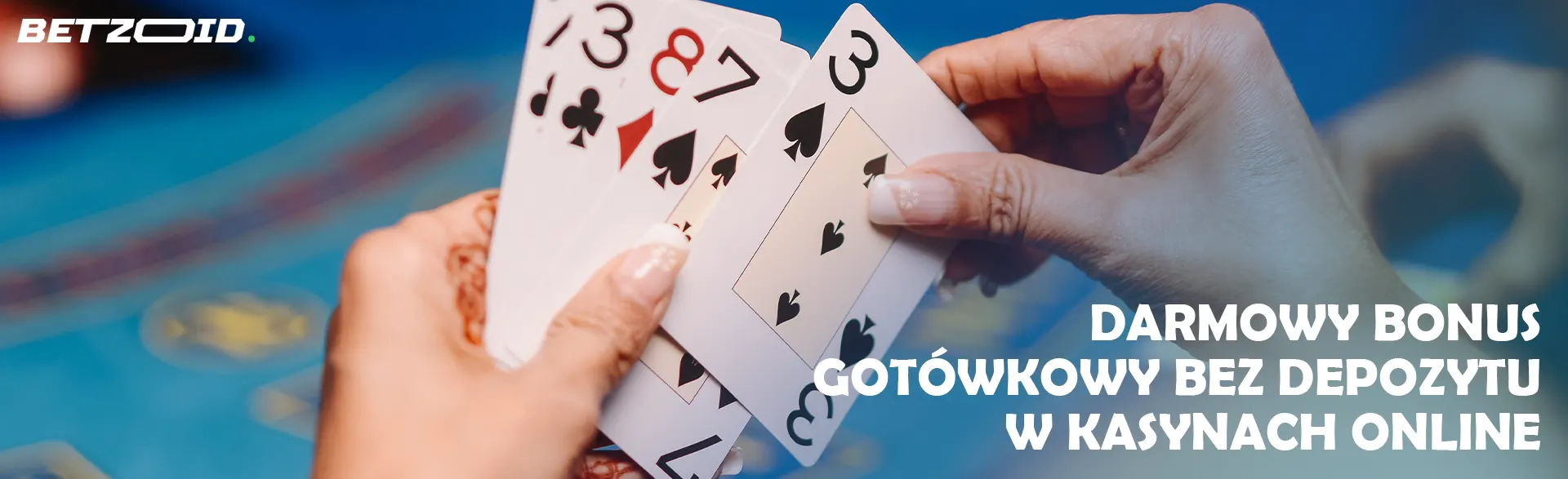 Gracz trzyma karty na tle stołu w kasynie.