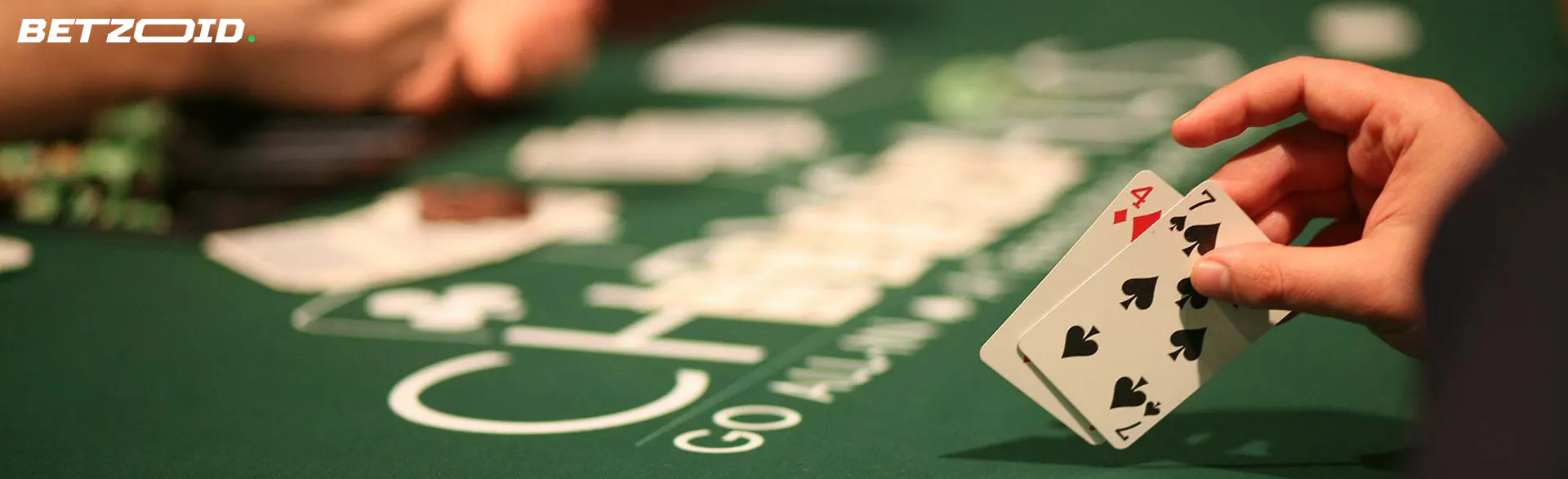 A player holds two cards on a green poker table.
