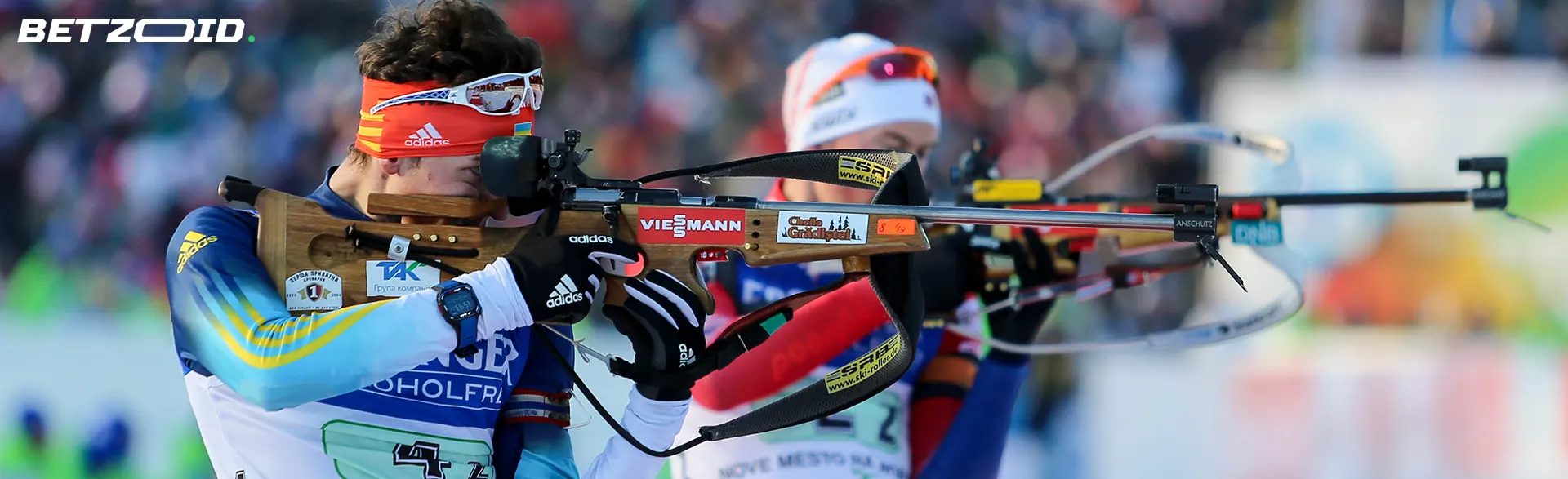 Biathleten zielen mit Gewehren in der Hand.