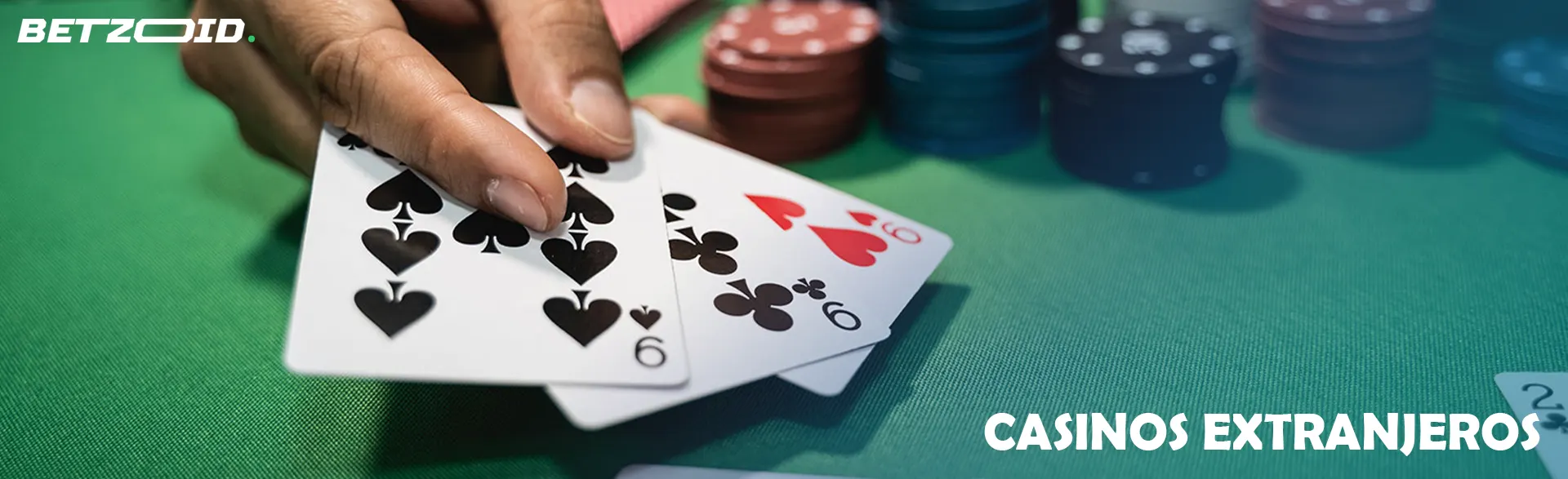 Mano sosteniendo cartas sobre mesa verde con fichas de casino.