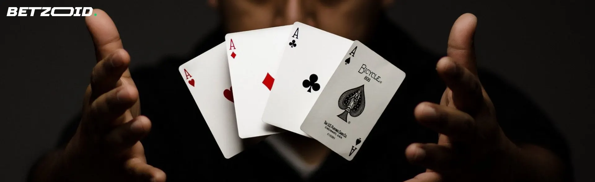 A man holds four cards in the air.