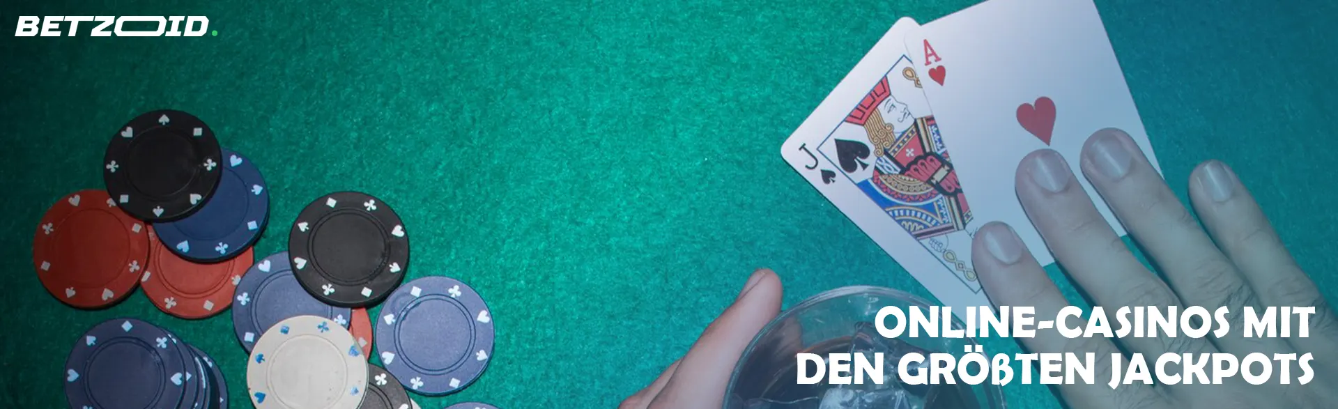 Ein Spieler hält Karten neben Casino-Chips und einem Getränk in einem Glas.