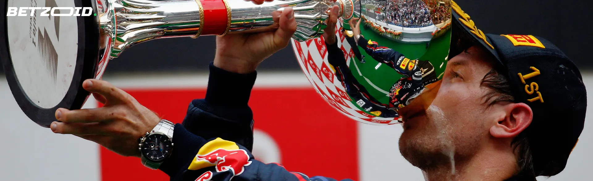 The racer drinks from the won cup.