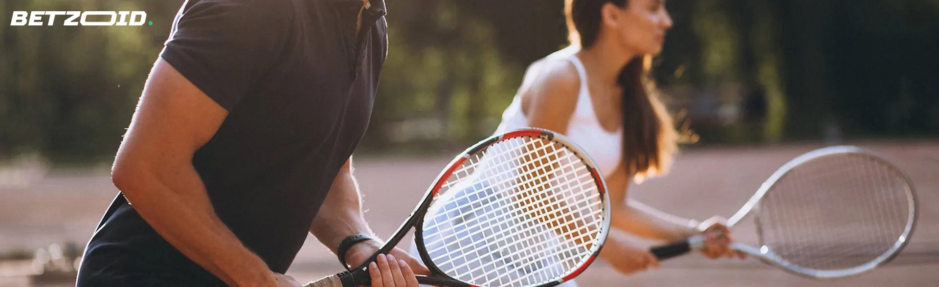 Un hombre y una mujer sostienen raquetas, preparándose para golpear para casas de apuestas con deposito minimo 10 euros.