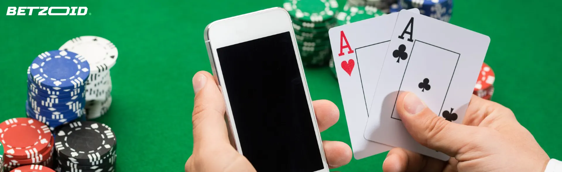 Smartphone y cartas en la mano del jugador junto a fichas de casino.