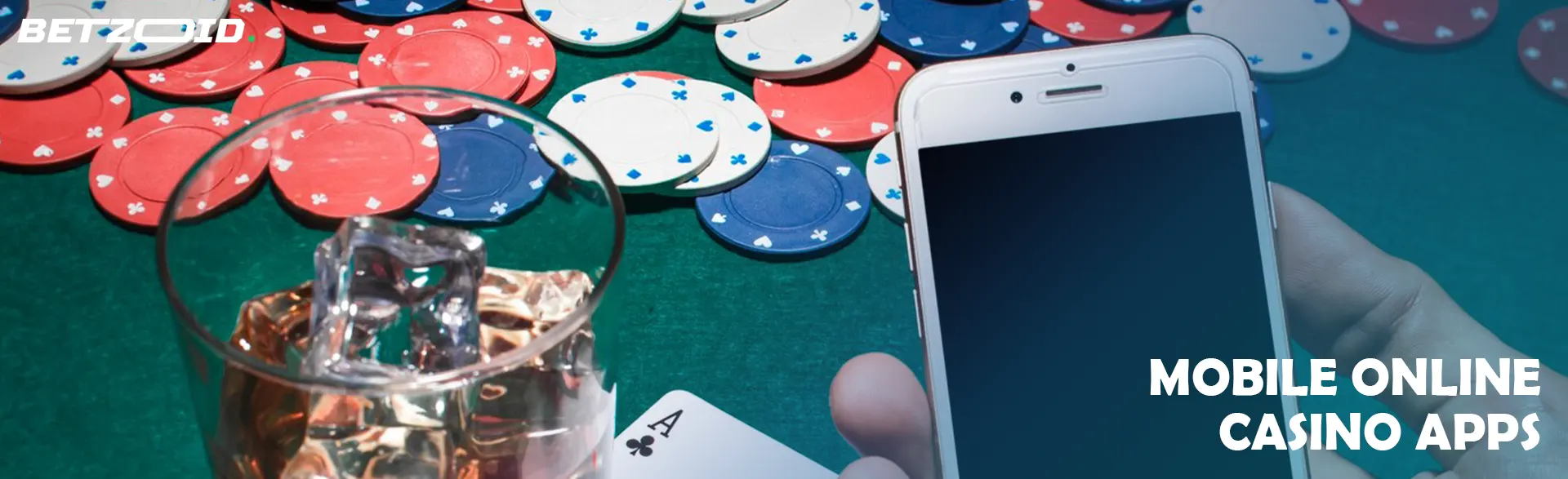 A gambler holds a smartphone next to a glass of drink on a background of casino chips.