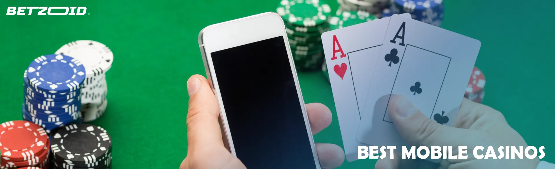 Cards and a smartphone in the hands of the player on the background of the casino table.
