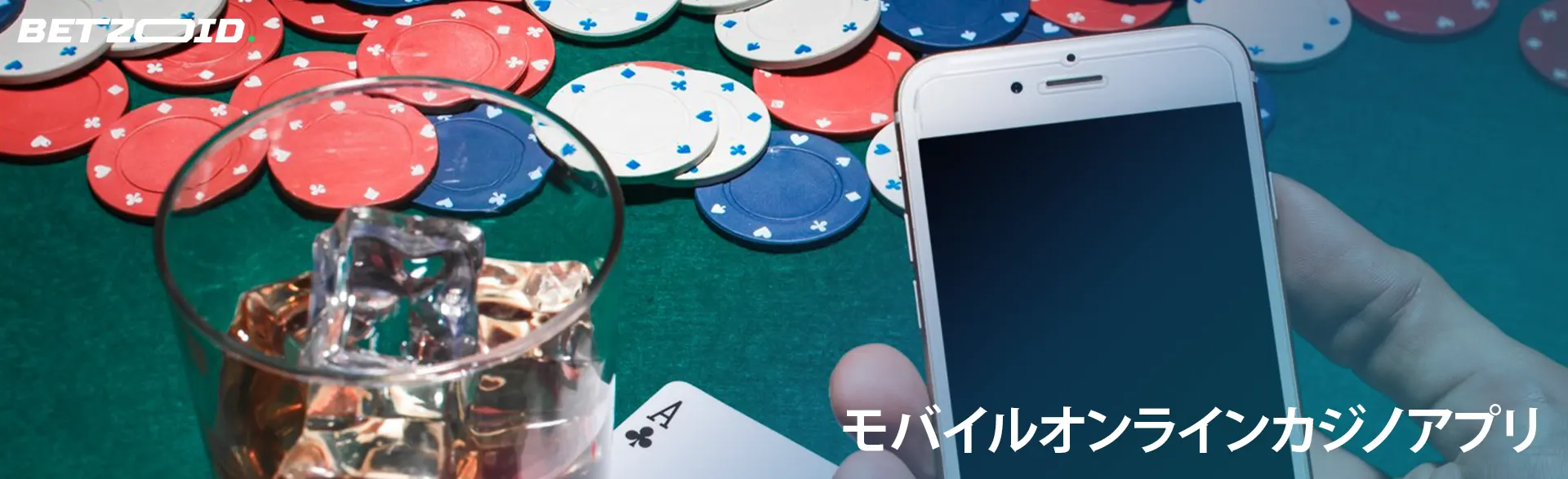 カジノチップの背景にあるグラスに入った飲み物の横にあるスマートフォン。