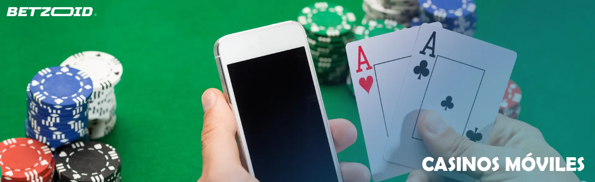 Un jugador sostiene un teléfono inteligente y cartas junto a fichas de casino.