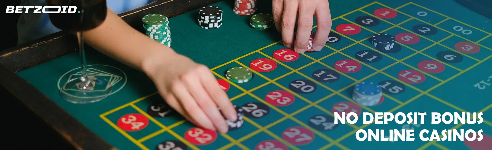 Players place bets on roulette next to a glass of drink.