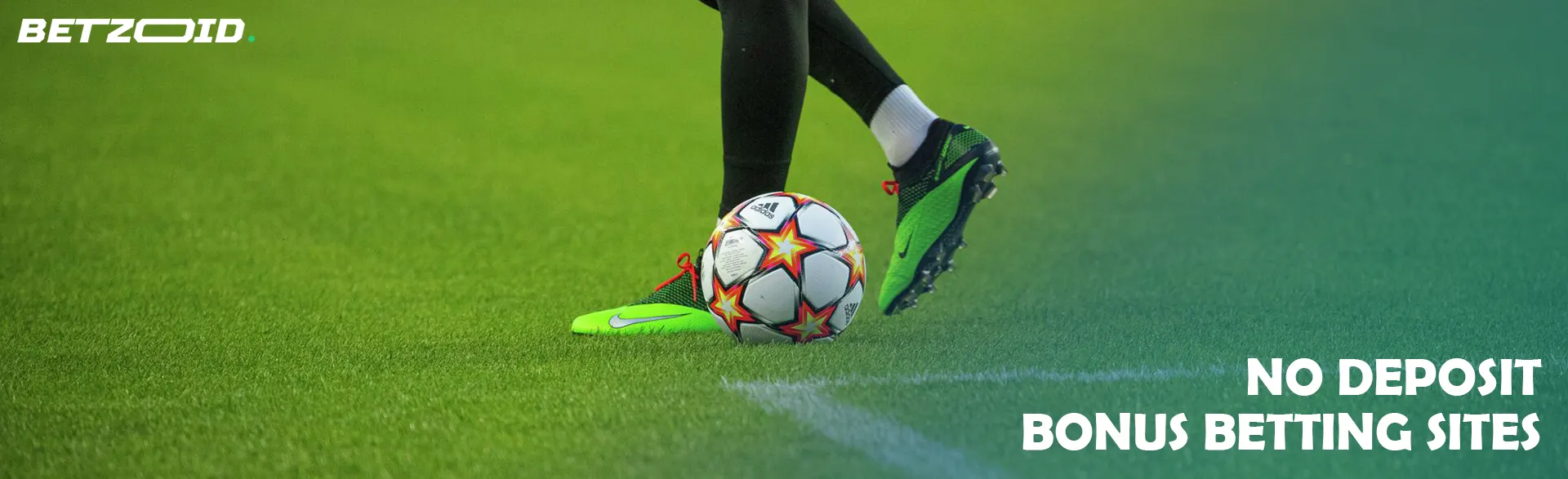 The legs of a football player kicking a soccer ball.