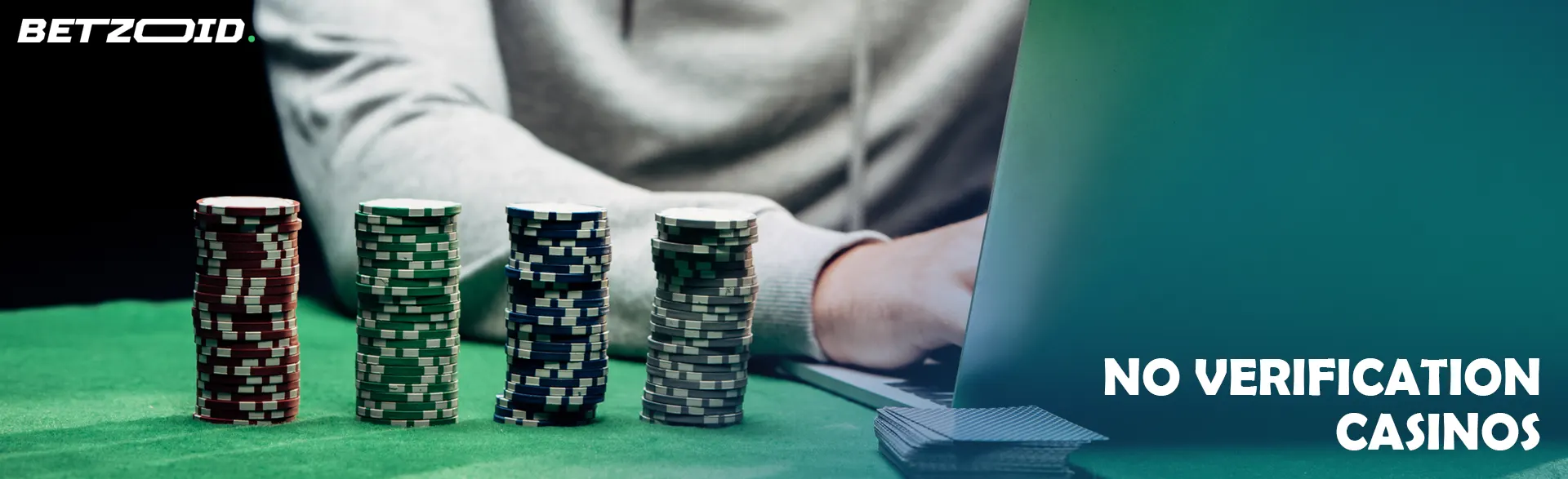 A player at a laptop next to stacks of casino chips.