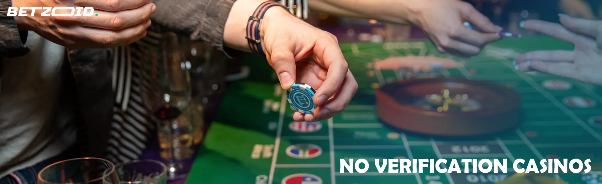 A player holds chips over a roulette table.