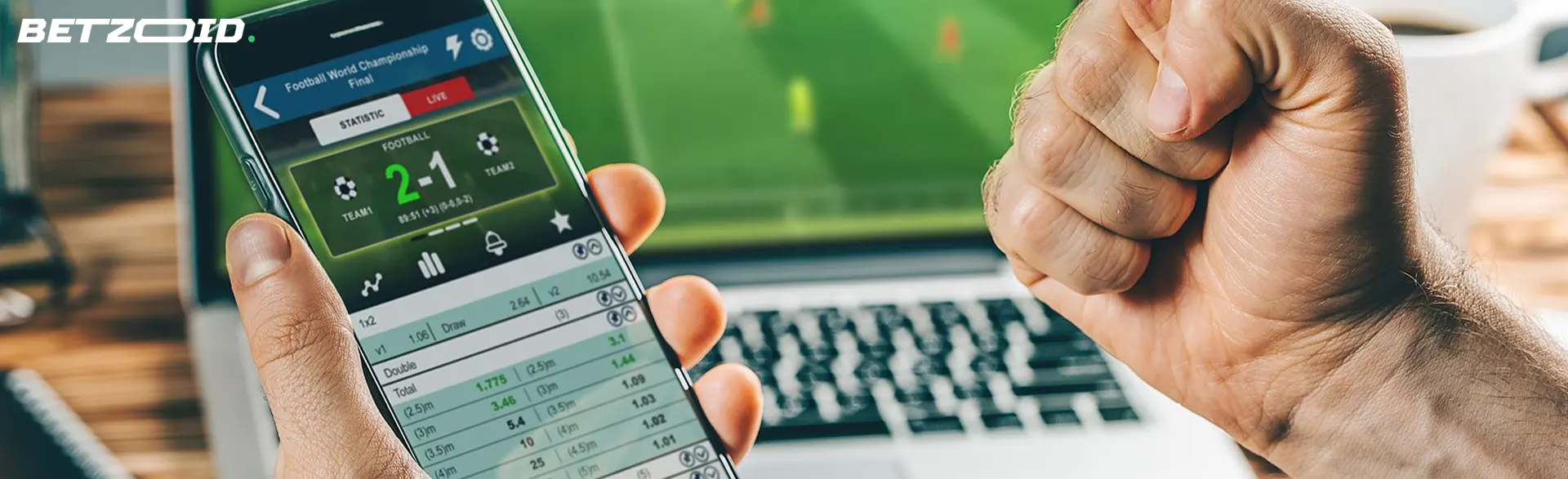 Mano sosteniendo el teléfono con resultados de apuestas deportivas.