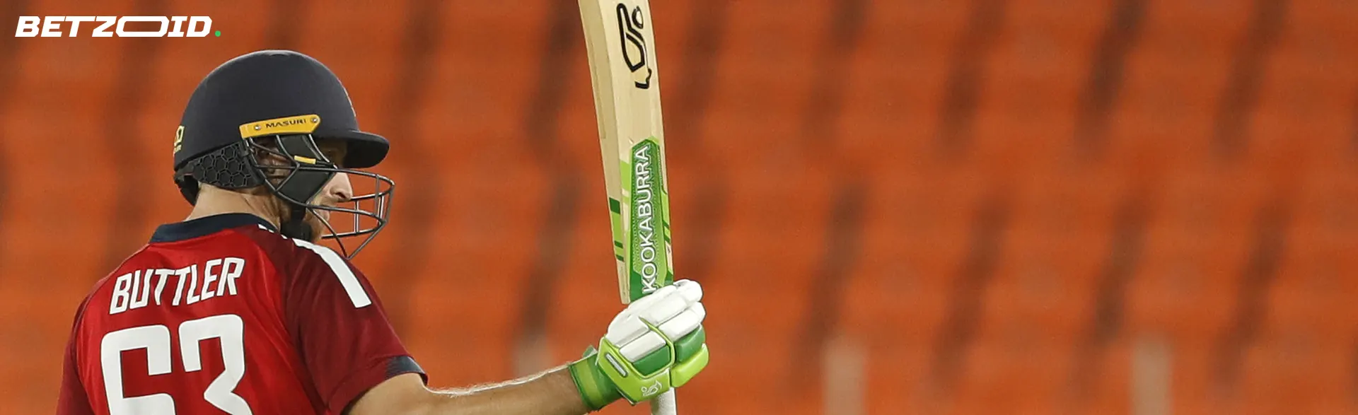 A cricketer with a bat on the background of the stands.