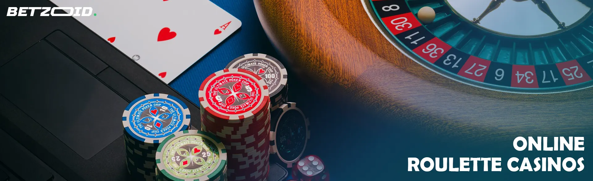 Roulette wheel and cards next to chips on laptop keyboard.