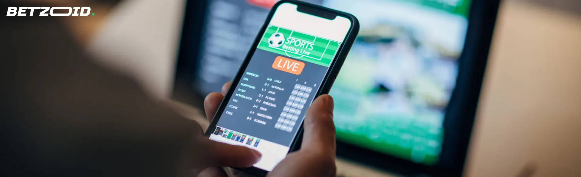 Person using a mobile phone to access a sports betting app with live football match scores displayed.