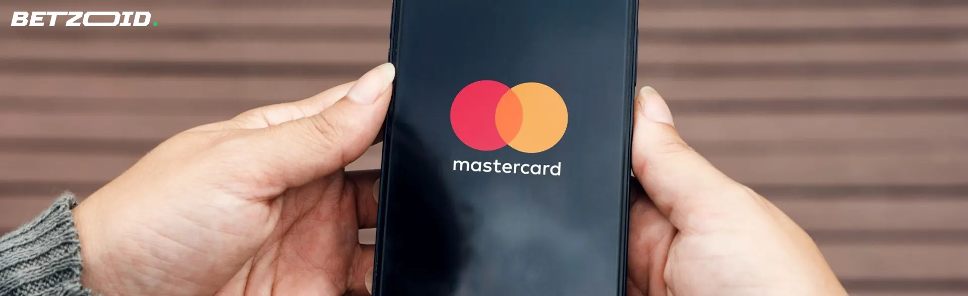 Mann hält Smartphone mit Mastercard-Logo.