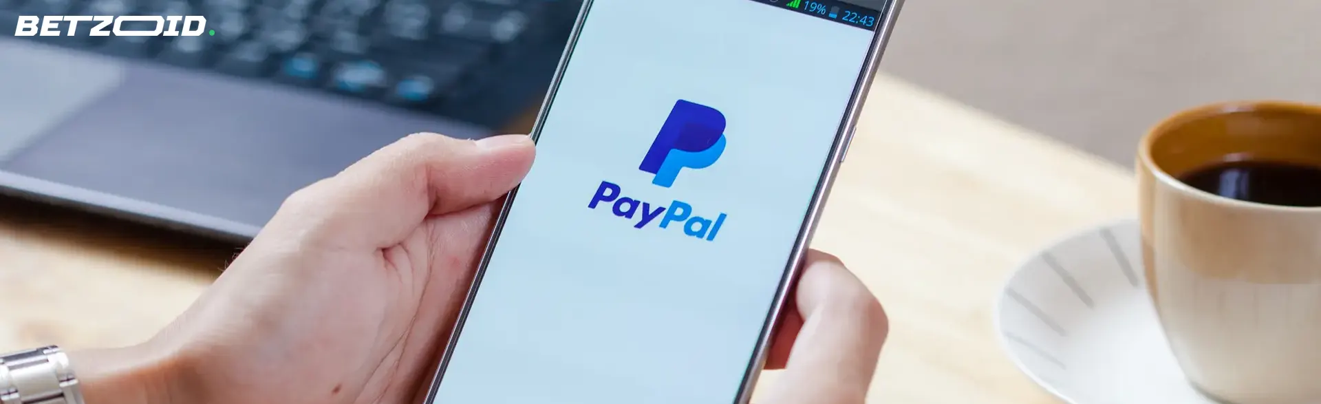 Una persona sostiene un teléfono inteligente con el logotipo de PayPal en la pantalla.