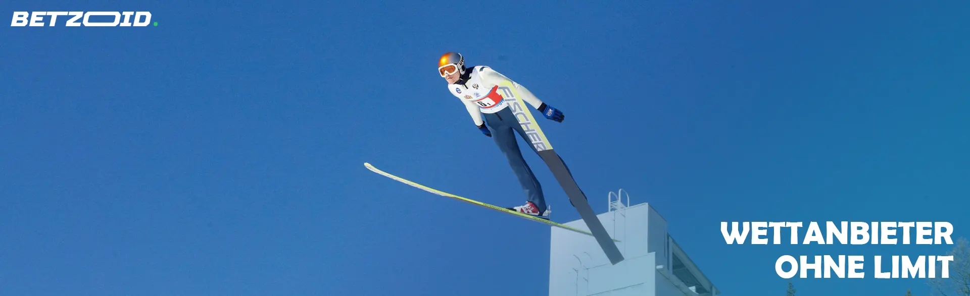 Ein Sportler springt auf Skiern von einer Schanze.
