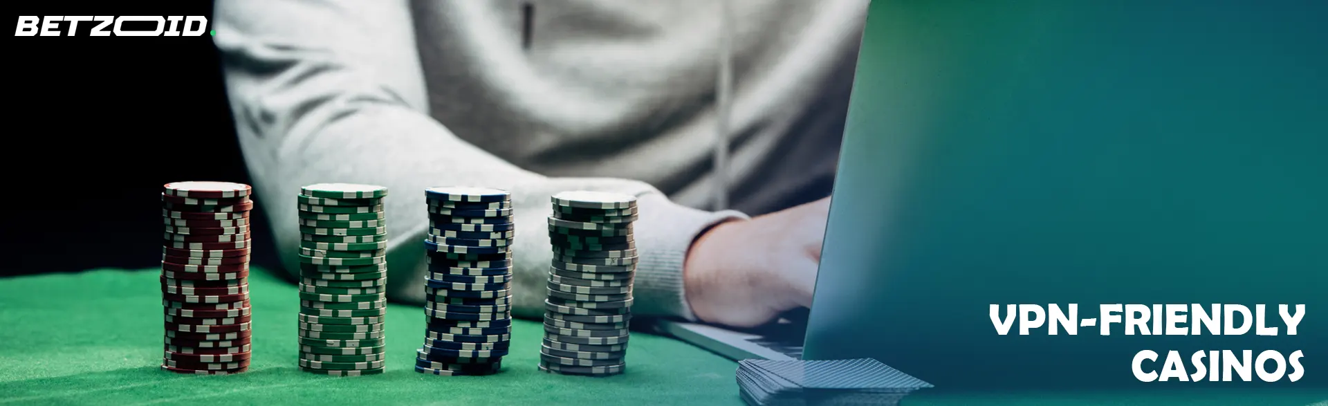 Stacks of poker chips next to a man at a laptop.